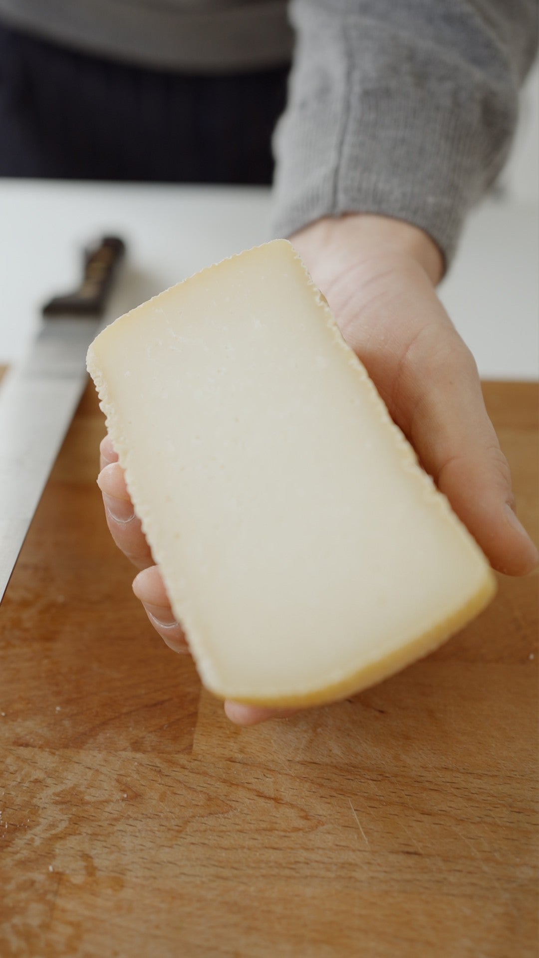 pecornino calabrese semiduro tagliato a metà e tenuto in mano.